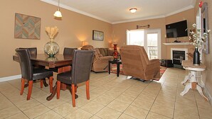 Una sala de estar con una mesa de comedor, sillas, sofás, chimenea y televisor.
