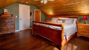 Une chambre à coucher avec un plafond en bois, un lit, une table de chevet et une commode.