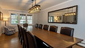 A dining room with a long wooden table, six chairs, a chandelier, and a large mirror on the wall. - Resort Style backyard including professional PICKLEBALL COURT paddles & HOT TUB. (southampton)
