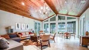 A spacious living room with a high ceiling, large windows, and a dining area.