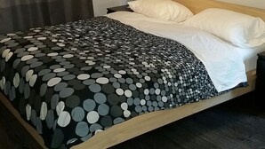 A bedroom with a bed, a ceiling fan, a painting, and a nightstand.