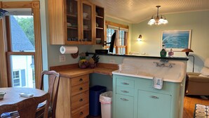 A kitchen with wooden cabinets, a countertop, a sink, and a dining area with a table and chairs.