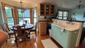 A kitchen with wooden cabinets, a central island with a sink, and a dining area with a table and chairs.