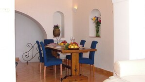 A dining area with a wooden table, blue chairs, and a vase of flowers on the wall. - great sea view - great position - not far from the town center (Positano)