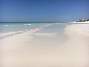 A beach with clear blue water and a sandy shore.