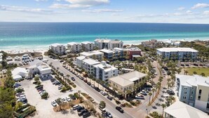 An aerial view of a coastal hotel area with multiple buildings, parking lots, and a beach in the background. - Gulf Place Caribbean - Top Rated Condo on 30-A with Pickleball & Tennis! (Santa Rosa Beach)