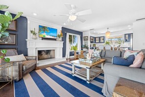 A living room with a fireplace, a television, a ceiling fan, and a striped rug. - Eagle Nest/Your Private Waterfront Escape on Florida's Nature Coast. (Hernando Beach)