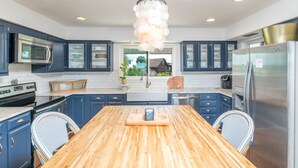 Uma cozinha moderna com armários azuis, uma mesa de madeira e eletrodomésticos de aço inoxidável.