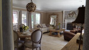 A living room with a sofa, a dining table with chairs, a coffee table, and a fireplace. - Beautiful Spanish style home- Garden. Fremont, California.  (Fremont)