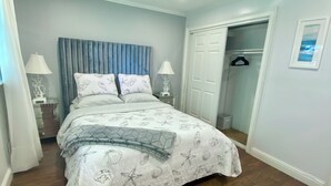 A bedroom with a bed, bedside tables, a wardrobe, and a door leading to another room.