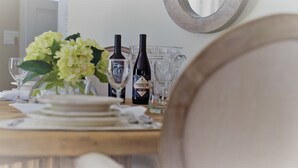 A dining table with a bottle of wine, glasses, and a vase of flowers.