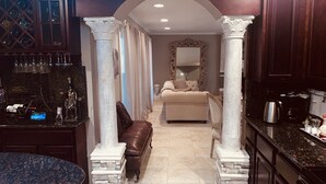 A luxurious hotel room with a marble floor, a large bed, a sitting area with a leather sofa, and a bar area with a wine cooler and bar stools. - Beautiful Spanish style home- Garden. Fremont, California.  (Fremont)