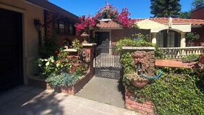 A residential property with a gated entrance, a garage, and a well-maintained garden with various plants and flowers.