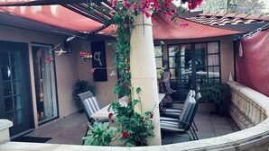 An outdoor patio with a covered seating area, a statue, and potted plants.
