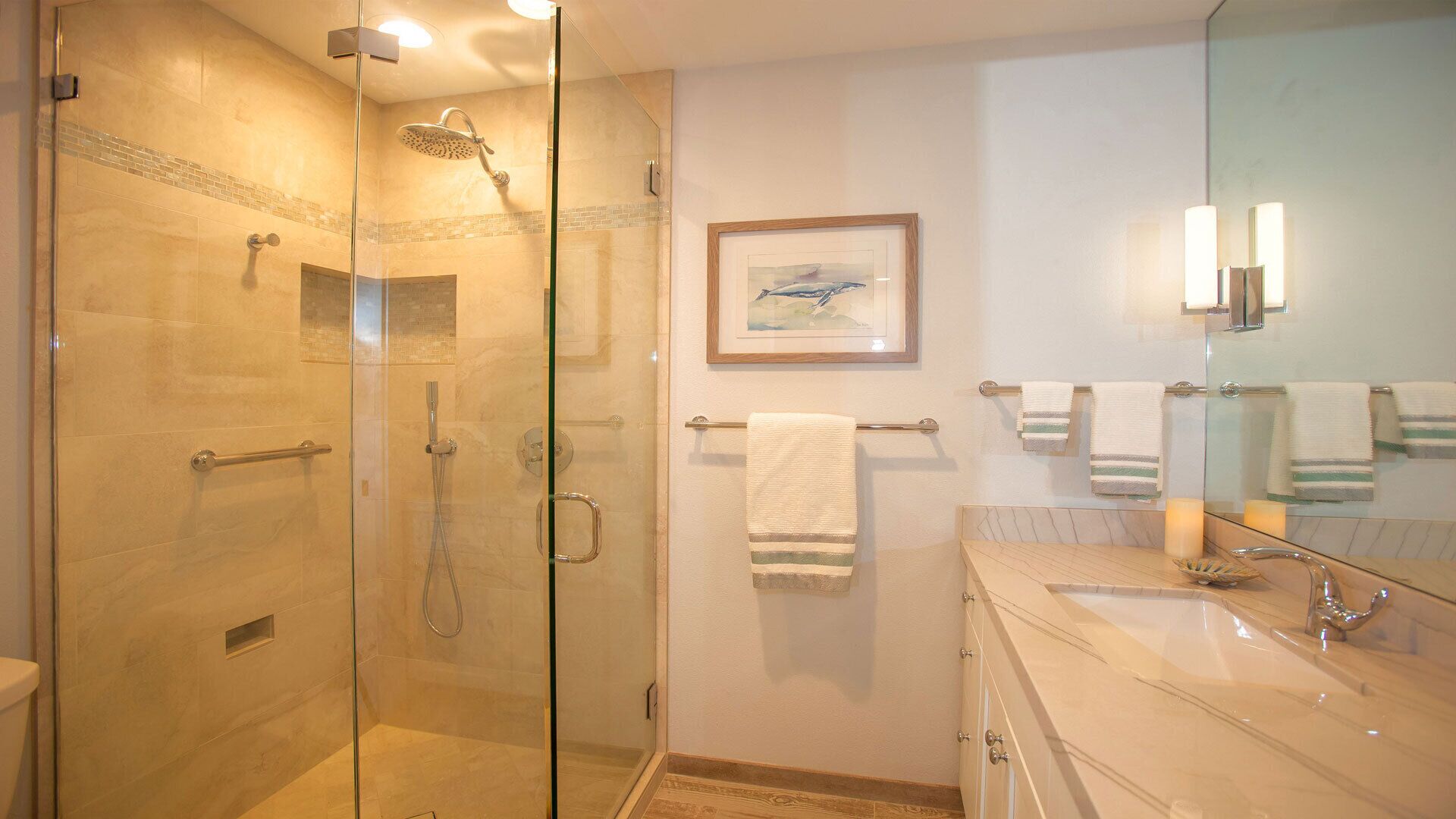 A modern bathroom with a glass-enclosed shower, a large mirror, and a vanity with a sink.