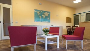 A room with three red chairs, a white table, and a world map on the wall. - Il Moscardino Country Resort (Serra San Bruno)