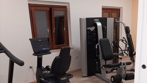 A home gym with a treadmill, elliptical, and weight machines. - Il Moscardino Country Resort (Serra San Bruno)