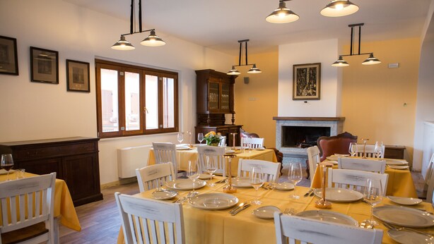 A dining area with tables set for a meal, chairs, and a fireplace. - Il Moscardino Country Resort (Serra San Bruno)