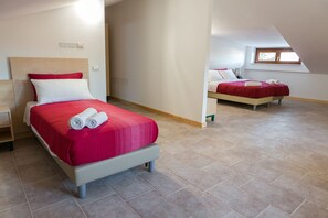 A hotel room with two beds, each with red bedding and white pillows. The room has a tiled floor and a sloped ceiling with a skylight. - Il Moscardino Country Resort (Serra San Bruno)