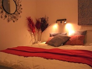 Cozy bedroom with a neatly made bed, wall-mounted mirror, and stylish lighting.