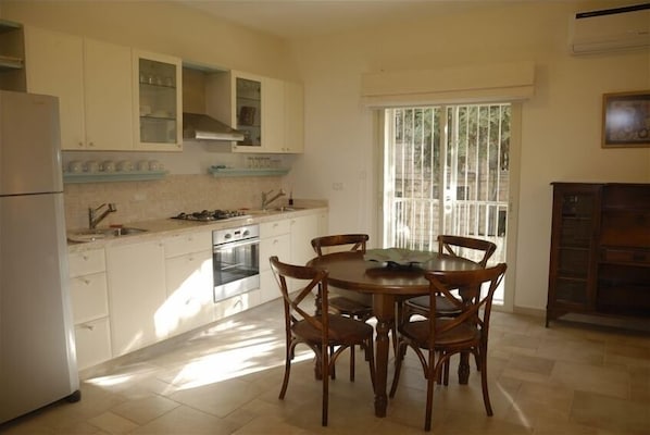 Enjoy meals in this kitchen with a dining table, refrigerator, stove, and central island.