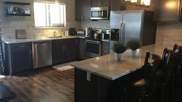 A modern kitchen with dark cabinets, stainless steel appliances, and a central island with chairs. - Beautifully Renovated South Lake Tahoe Condo  Minutes To Casinos, Ski & Beaches (Zephyr Cove)