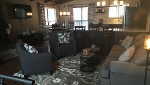 A living room with a sofa, armchair, and a coffee table. There is a kitchen area with a refrigerator, sink, and a dining table with chairs. - Beautifully Renovated South Lake Tahoe Condo  Minutes To Casinos, Ski & Beaches (Zephyr Cove)
