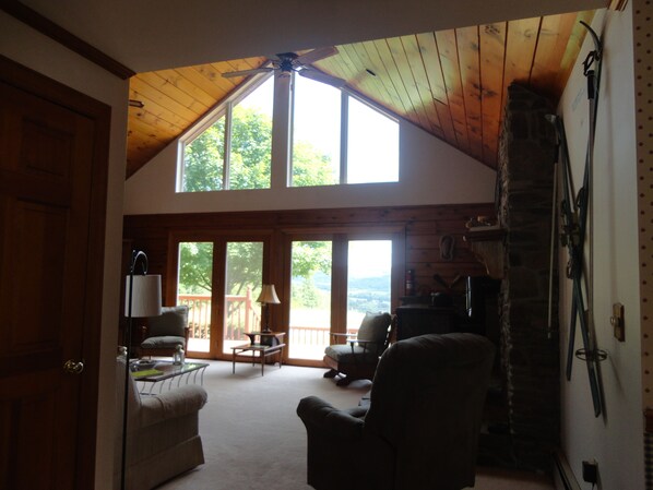 A spacious living area with a high ceiling, large windows, and a stone fireplace. - Western Catskills Paradise - Four-Season Mountaintop Retreat (Bainbridge)