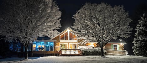 Une cabane en rondins avec une façade en bois et en verre, et une véranda.