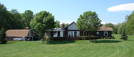 A residential property with a large lawn, a barn, and a house with a porch.