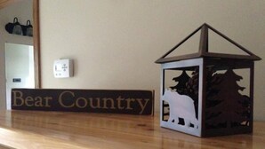 Uma placa de madeira com o texto 'Bear Country' e um candeeiro decorativo com silhueta de urso.