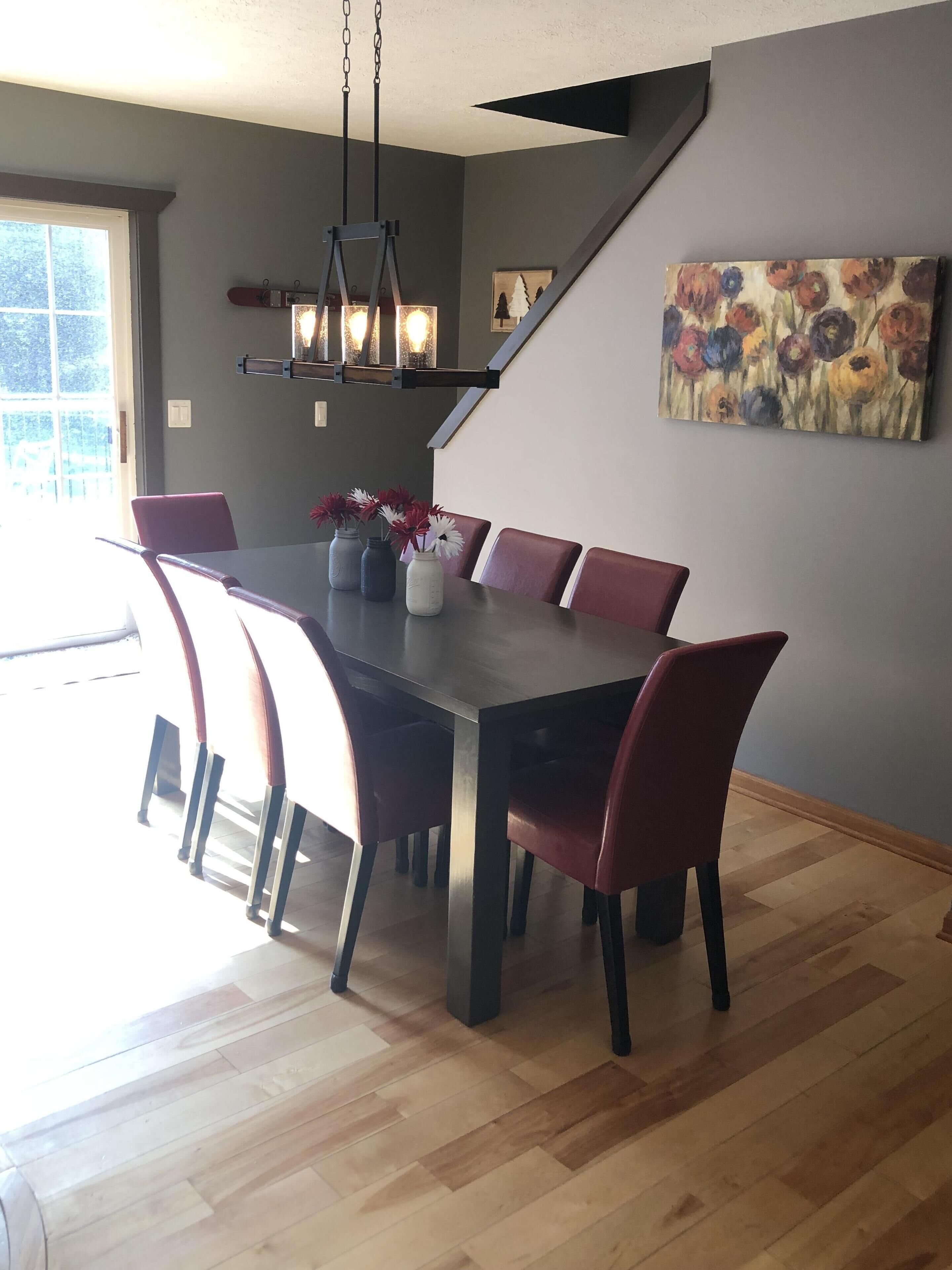 A dining area with a long table, red chairs, and a chandelier.