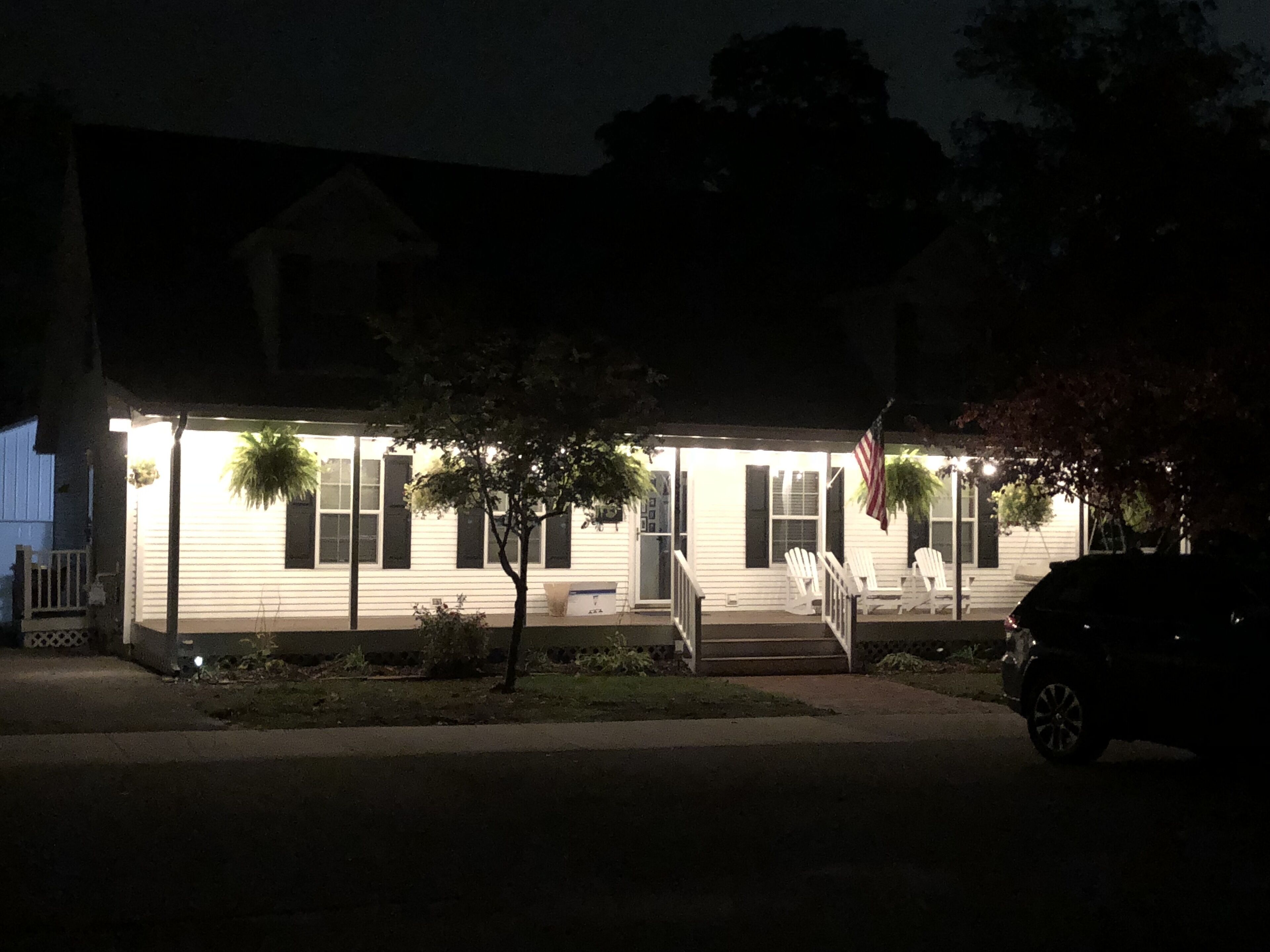 A two-story house with a porch, a small deck, and a flag.