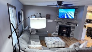 Een moderne woonkamer met een grijze modulaire bank, een open haard en een flatscreen televisie erboven.