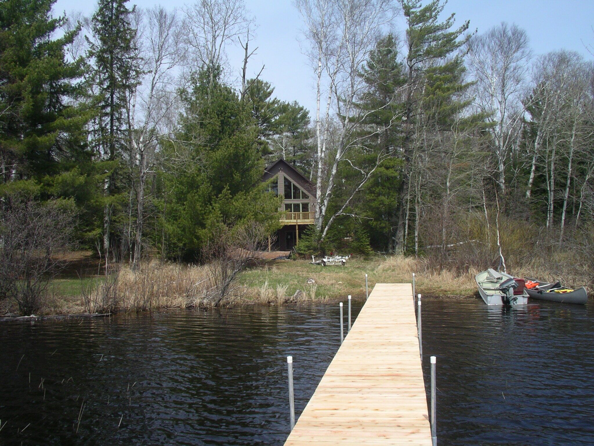 Une jetée en bois menant à un chalet entouré d’arbres.