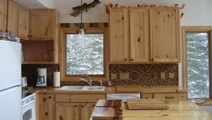 A kitchen with wooden cabinets, a large window, and a hanging fish decoration.