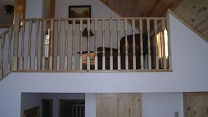 A wooden staircase with a railing leading to a second-floor balcony.