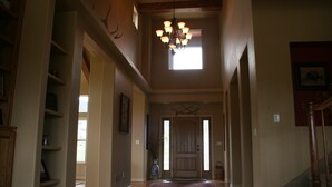 A spacious hallway with a wooden floor, a chandelier, and a door at the end. - 6000 sq ft Estate Home on 3 Acres near USAFA in the Rockies (Monument)