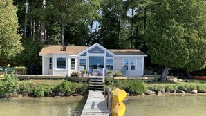 A house with a dock extending into a calm body of water, surrounded by trees. - Glen Lake  - Spectacular Dune Views & Complete Privacy! (Glen Arbor)