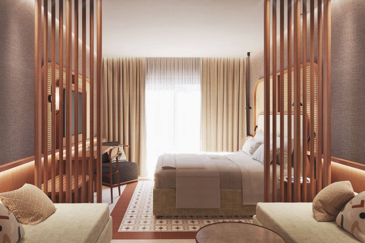 A modern hotel room with a bed, two sofas, a desk, and a large window with curtains.