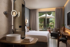 Habitación de hotel moderna con una cama grande, un lavamanos redondo, un espejo y vistas al exterior.