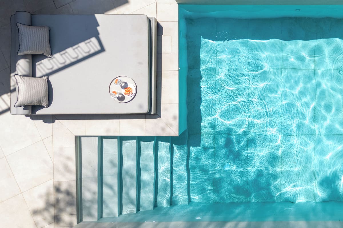 A rooftop pool with a sun lounger and a table with a drink tray.