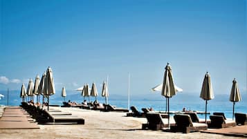 Vlak bij het strand, ligstoelen aan het strand, parasols, strandlakens
