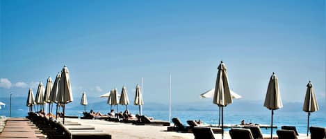 Vlak bij het strand, ligstoelen aan het strand, parasols, strandlakens