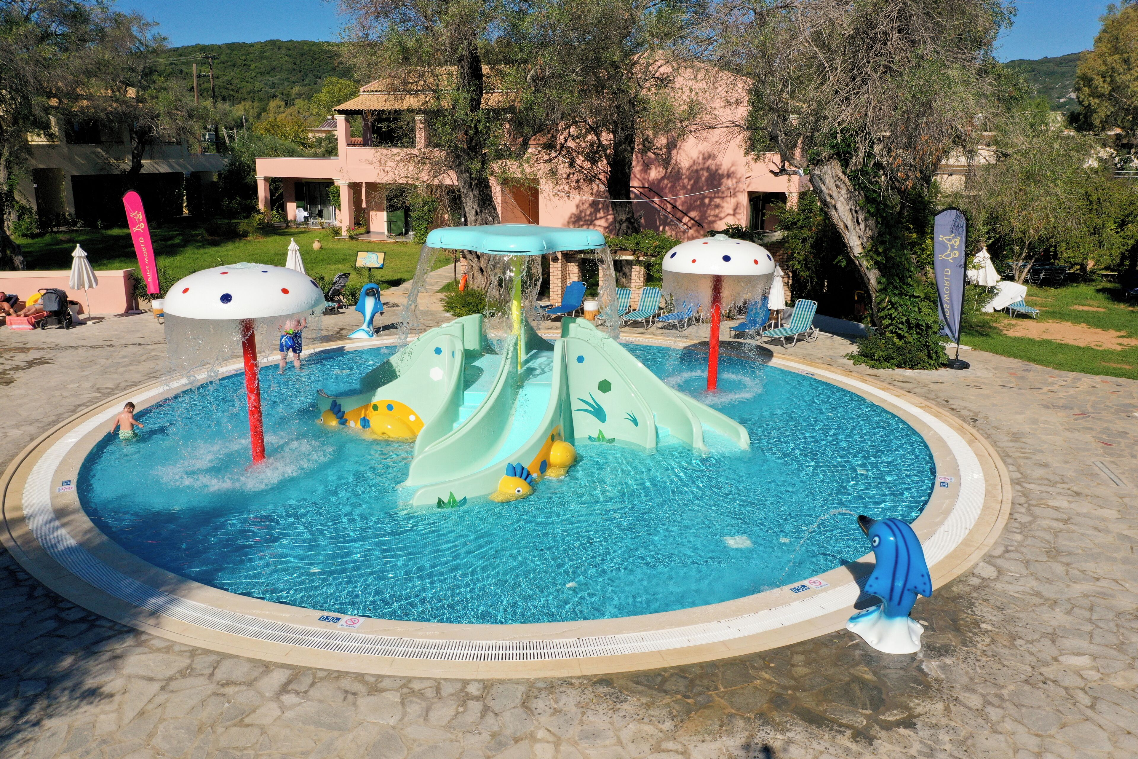Una piscina con toboganes y una pequeña isla con un paraguas azul.
