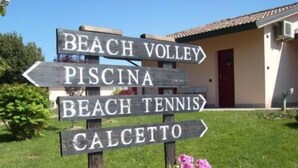A wooden signpost with directional arrows pointing to Beach Volley, Piscina, Beach Tennis, and Calcetto. - Hotel Giannina (Forlimpopoli)