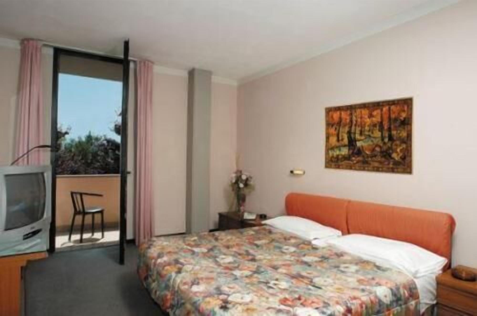 Une chambre d’hôtel avec un lit, une télévision, une table de chevet et un tableau au mur.