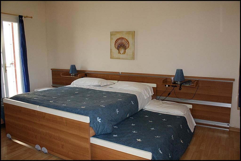 Ein Doppelbett mit Holzkopfstück, ein Nachttisch mit Lampe und ein an der Wand befestigtes Kunstwerk.