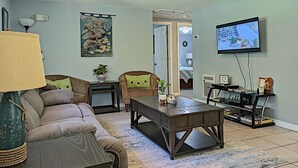 Ein Wohnzimmer mit Sofa, Couchtisch, Fernseher und Bücherregal.