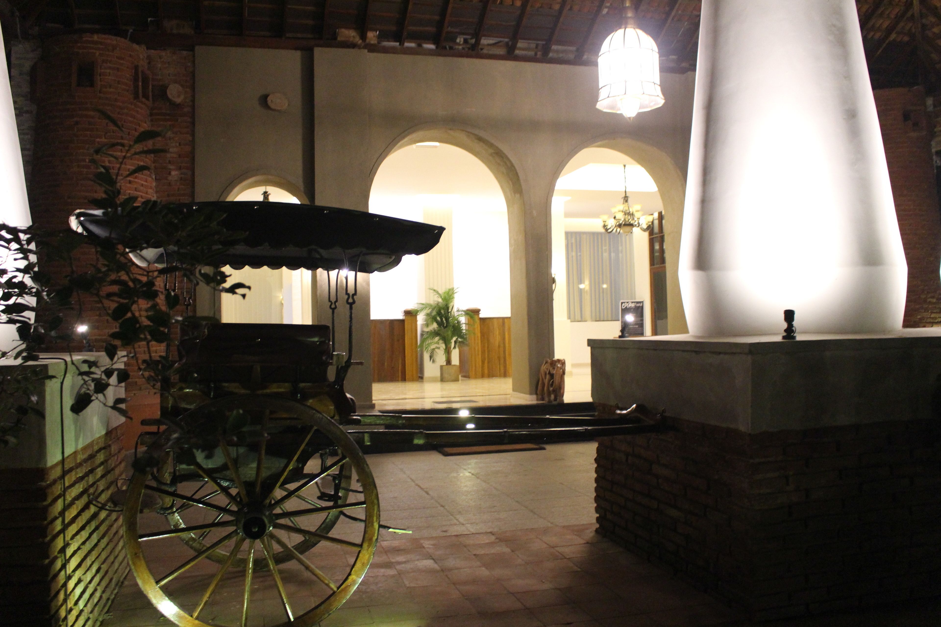 A courtyard with a vintage carriage, brick walls, and arched doorways.